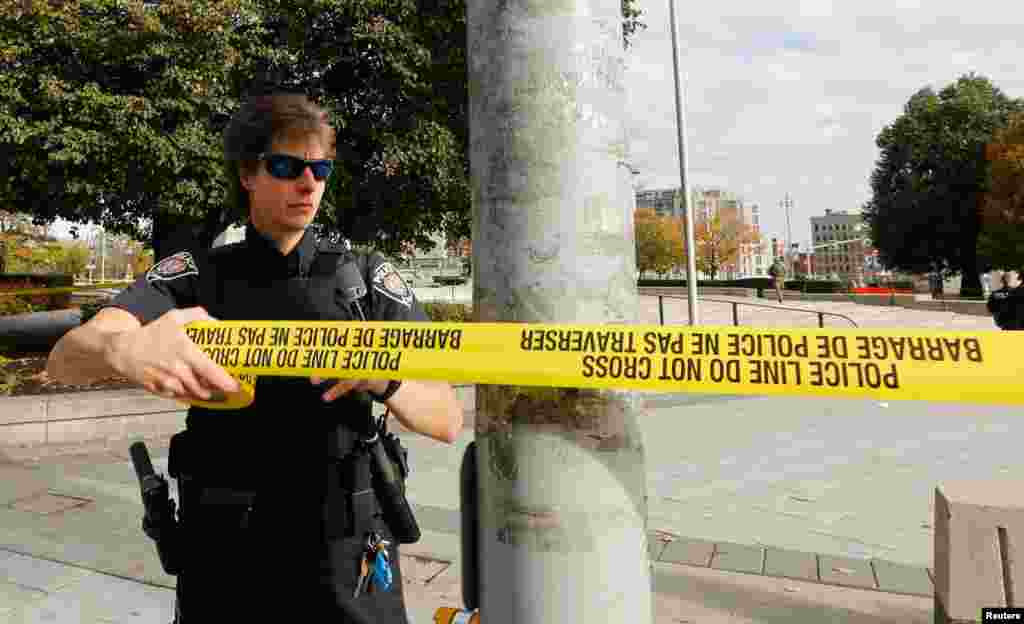 A police officer closes off the scene near the Canada War Memorial following a shooting incident in Ottawa. 